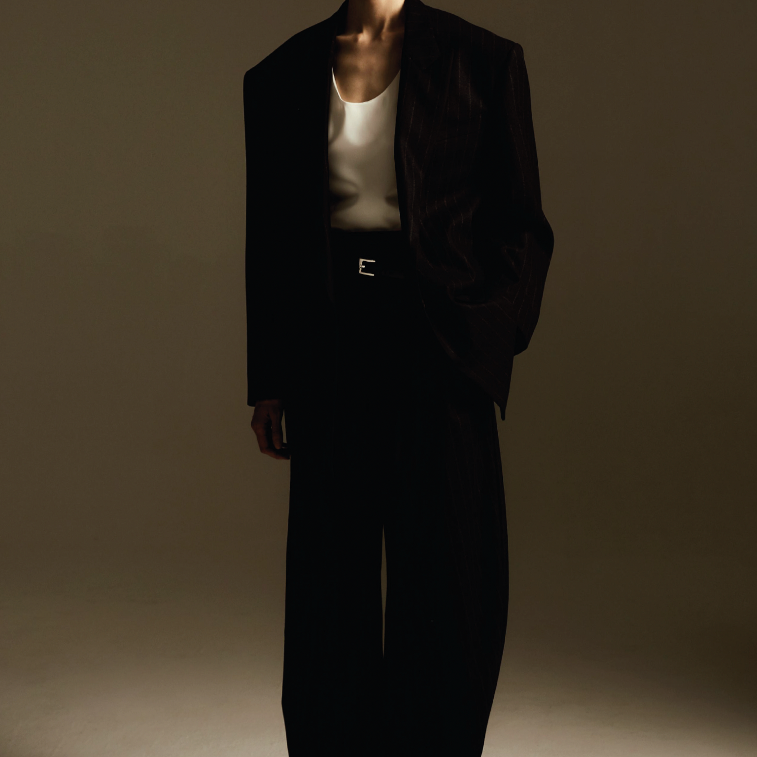 Women's Tailored custom made Person wearing a black pinstripe suit with a white blouse, standing against a plain background.