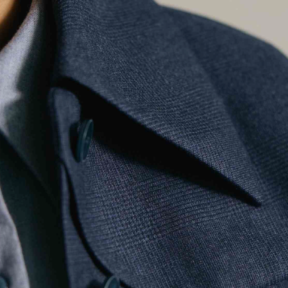 Women's Tailored custom made  Close-up of a dark navy blazer with the collar and buttons visible.