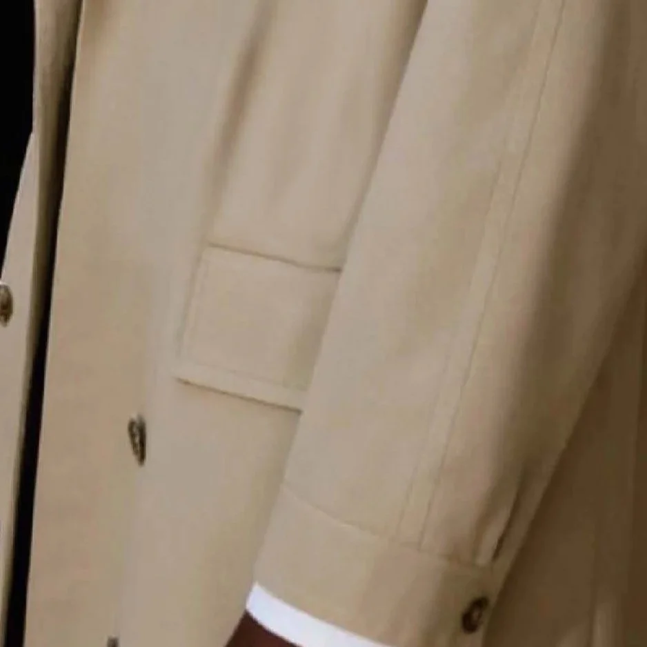 Close-up of a person in beige clothing standing near a closed door in BIA LUCINA.