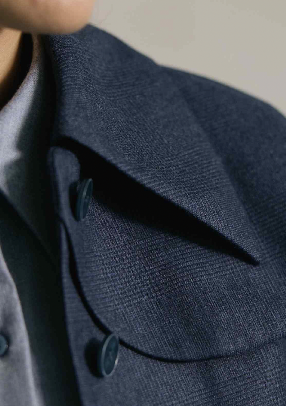 Women's Tailored custom made  Close-up of a dark navy blazer with the collar and buttons visible.
