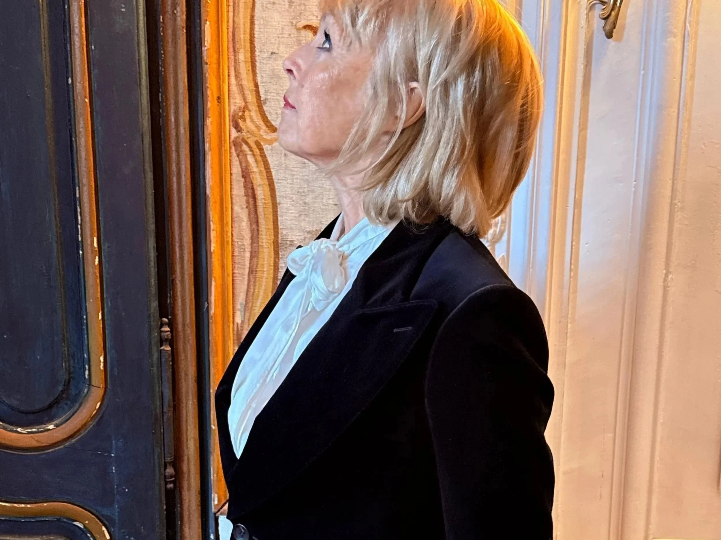 Profile of a woman with blonde hair playing a black upright piano.