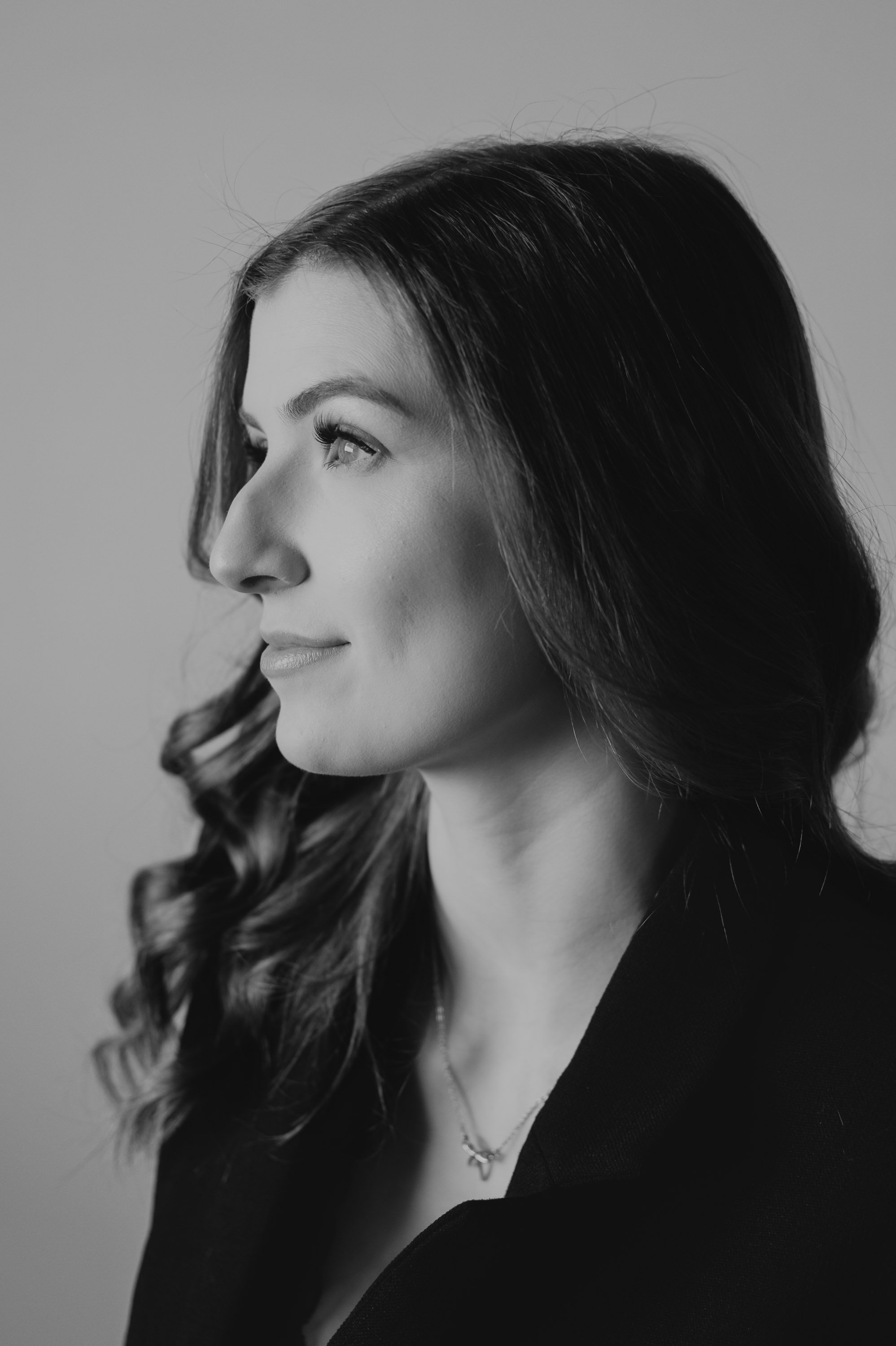 Black and white portrait of a woman with long, wavy hair looking to the left.