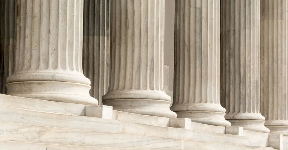 Close-up of marble columns with fluted shafts and circular bases, part of a classical building.