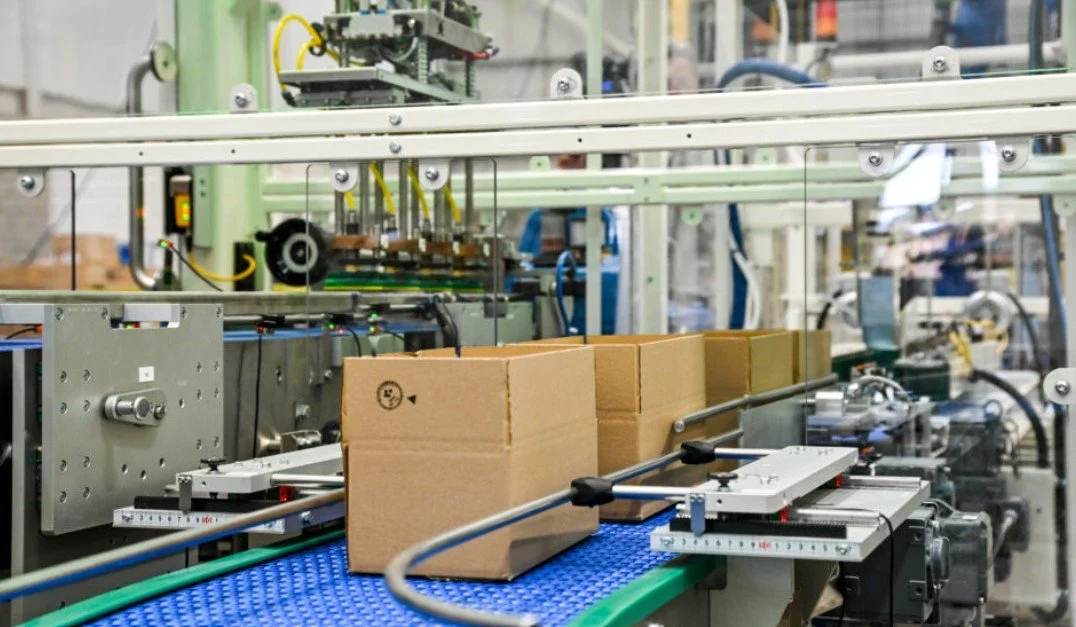 Automated packaging machine packing boxes on a conveyor belt in a factory.