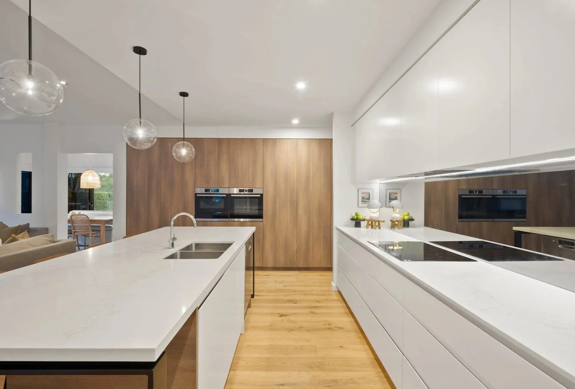 Modern kitchen with white countertops, wooden cabinets, and black appliances.