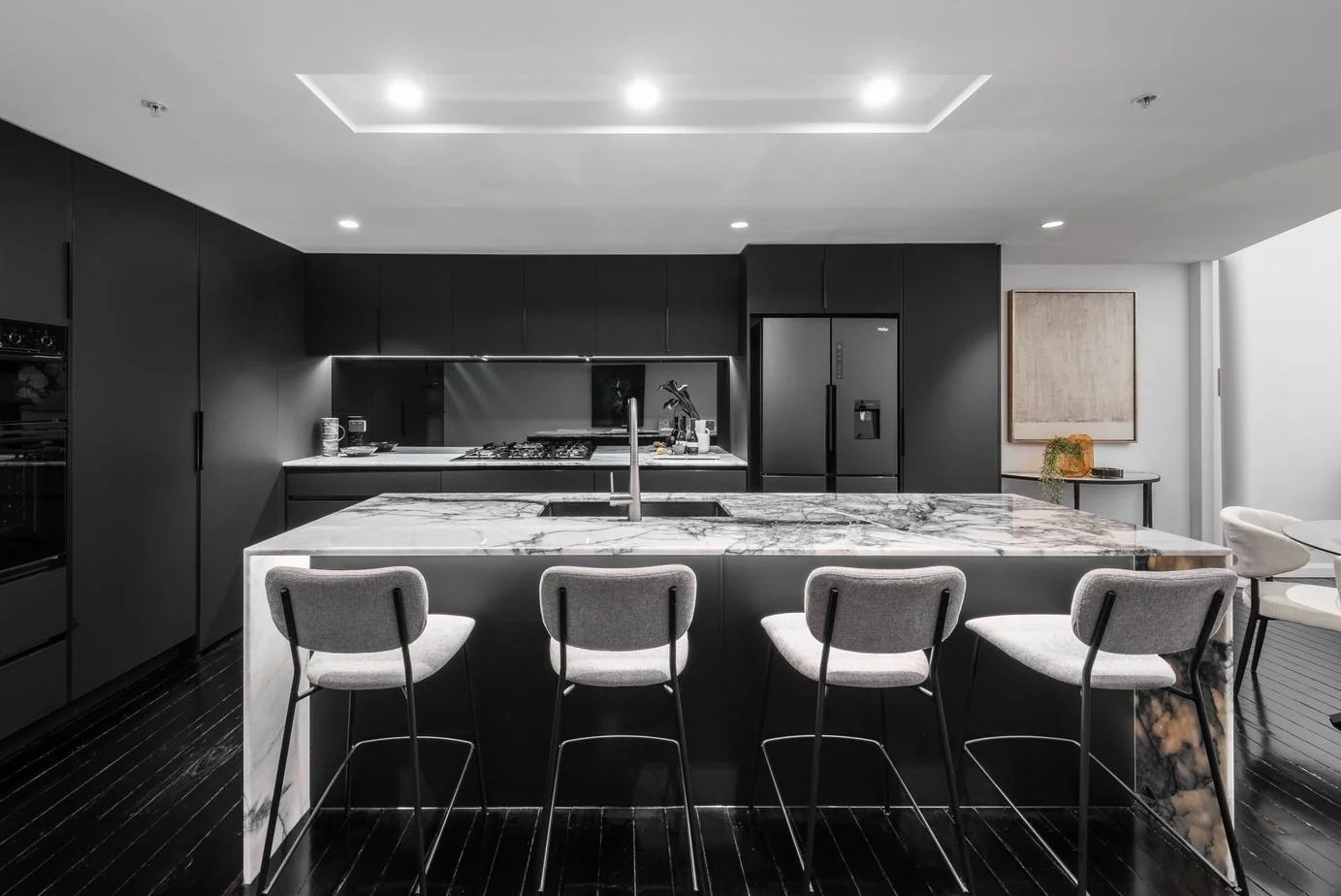 Modern kitchen with black cabinets and a white marble island with seating