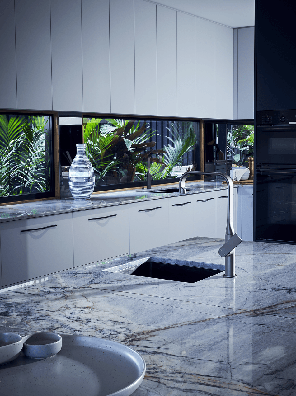 Modern kitchen with marble countertops and white cabinets, large window with view of green plants outside, black oven, and a tall white vase on the counter.