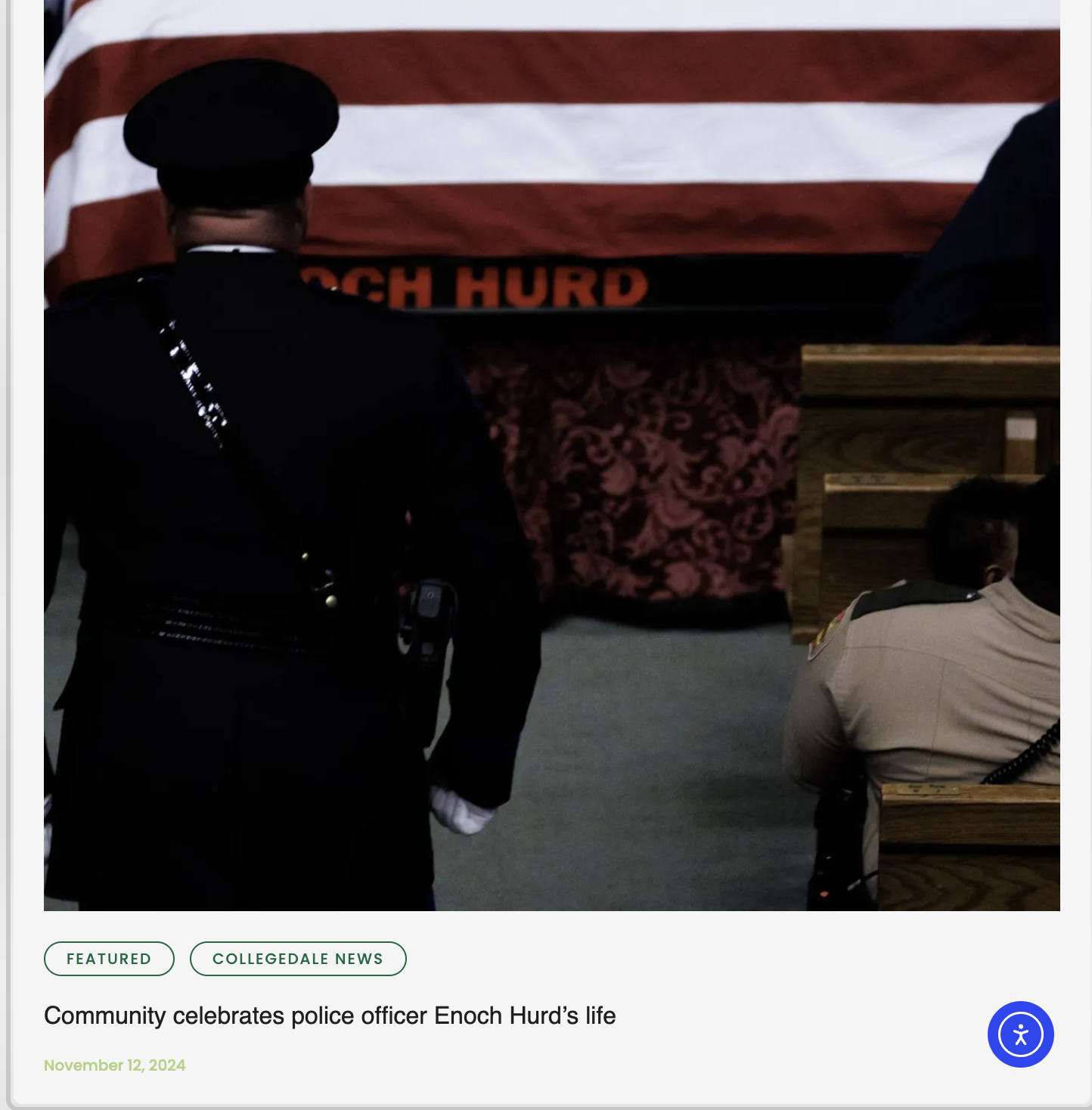 People gathered at a community event honoring police officer Enoch Hurd, with a display featuring a flag and a floral arrangement in the background.