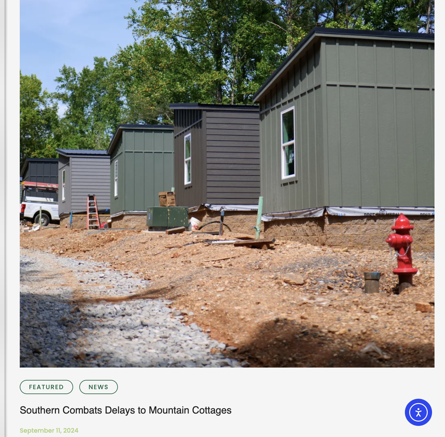 Construction site with newly built mountain cottages, dirt ground, and a red fire hydrant in the foreground.