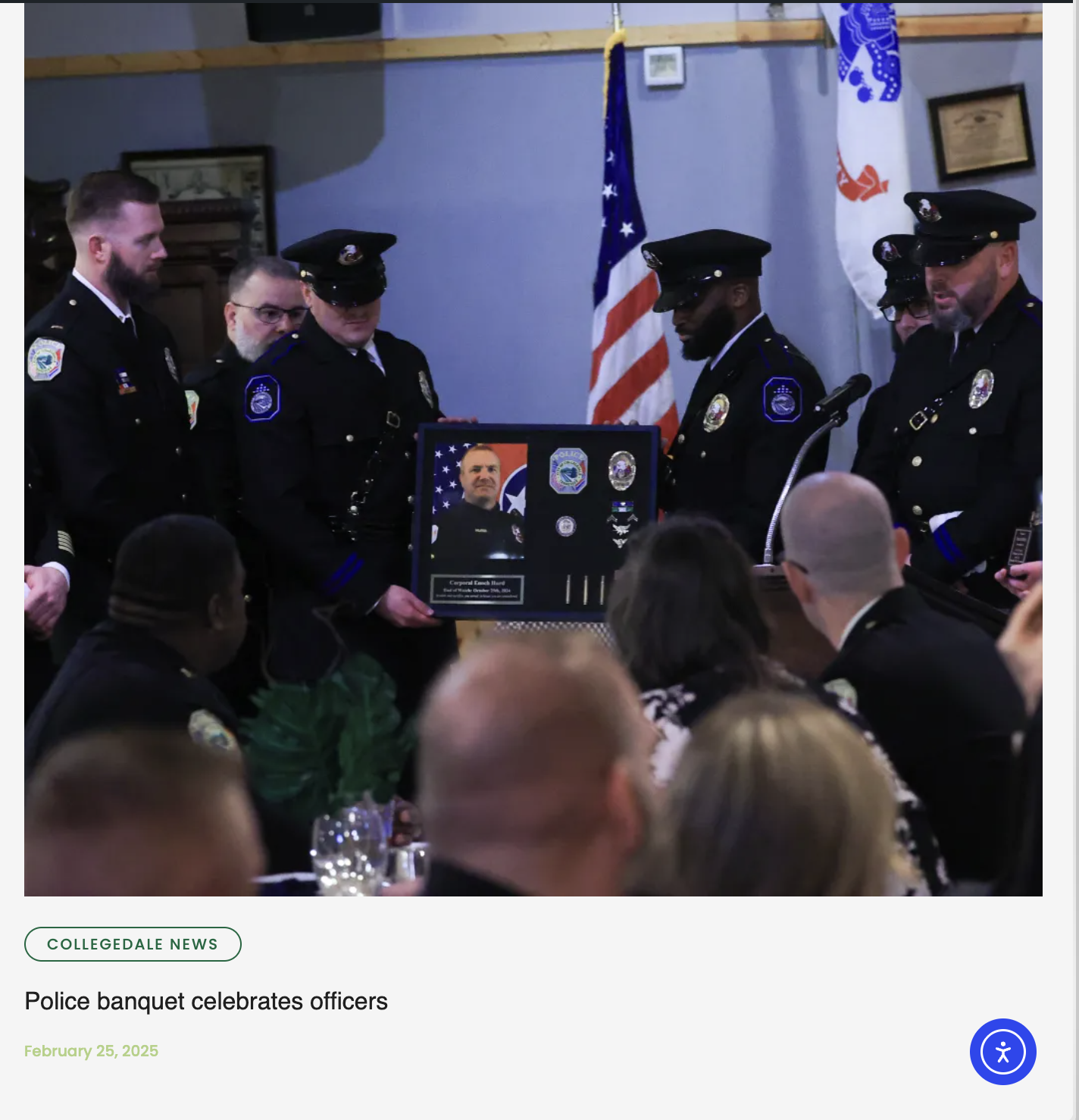 A police officer receiving a framed recognition plaque during a banquet, surrounded by other officers and attendees, with American flags in the background, at a formal police event.