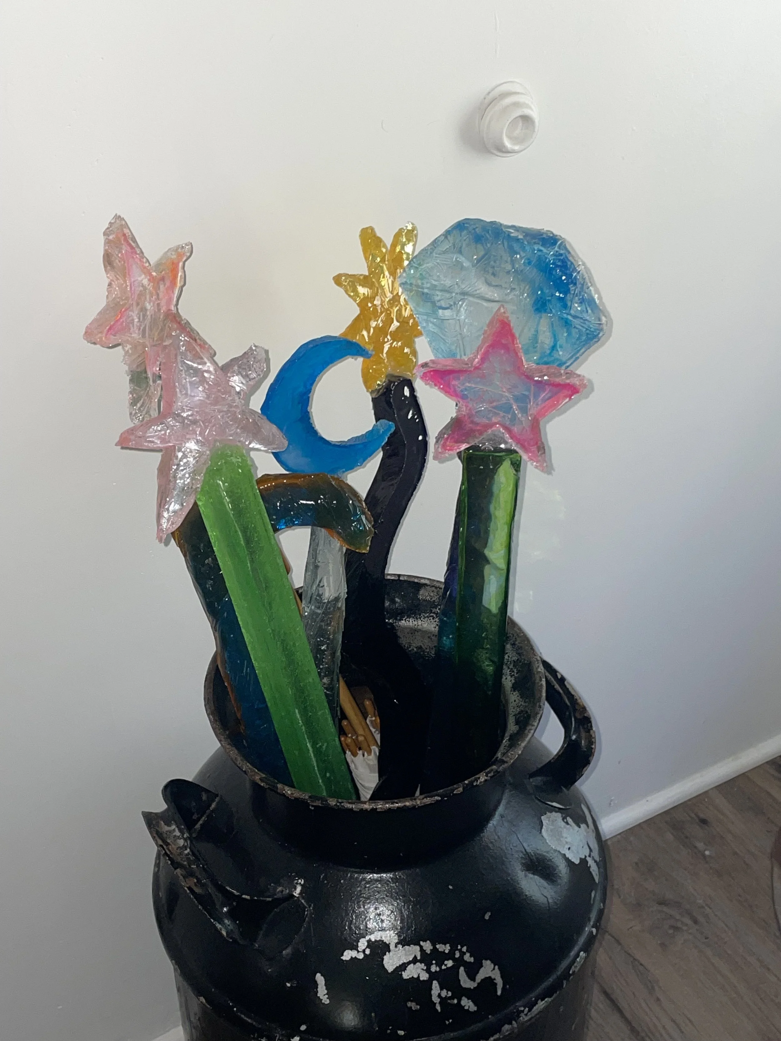 Colorful resin sculptures of stars, moons, and abstract shapes in a black vase.