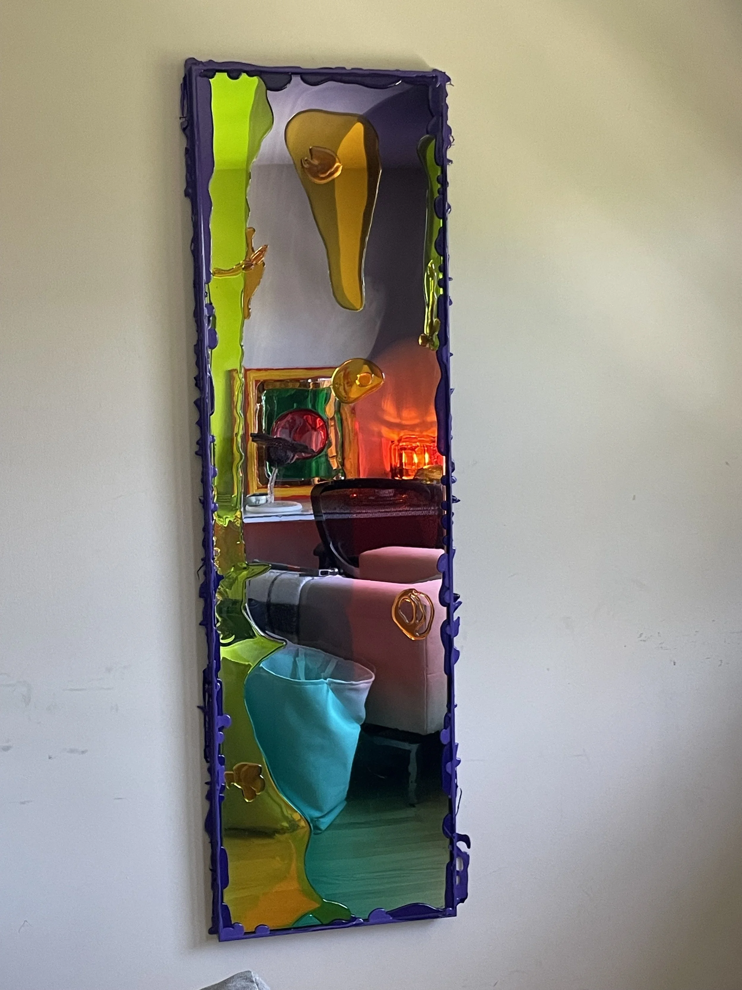 Colorful resin mirror with purple border reflecting a room with furniture and colorful decorations.