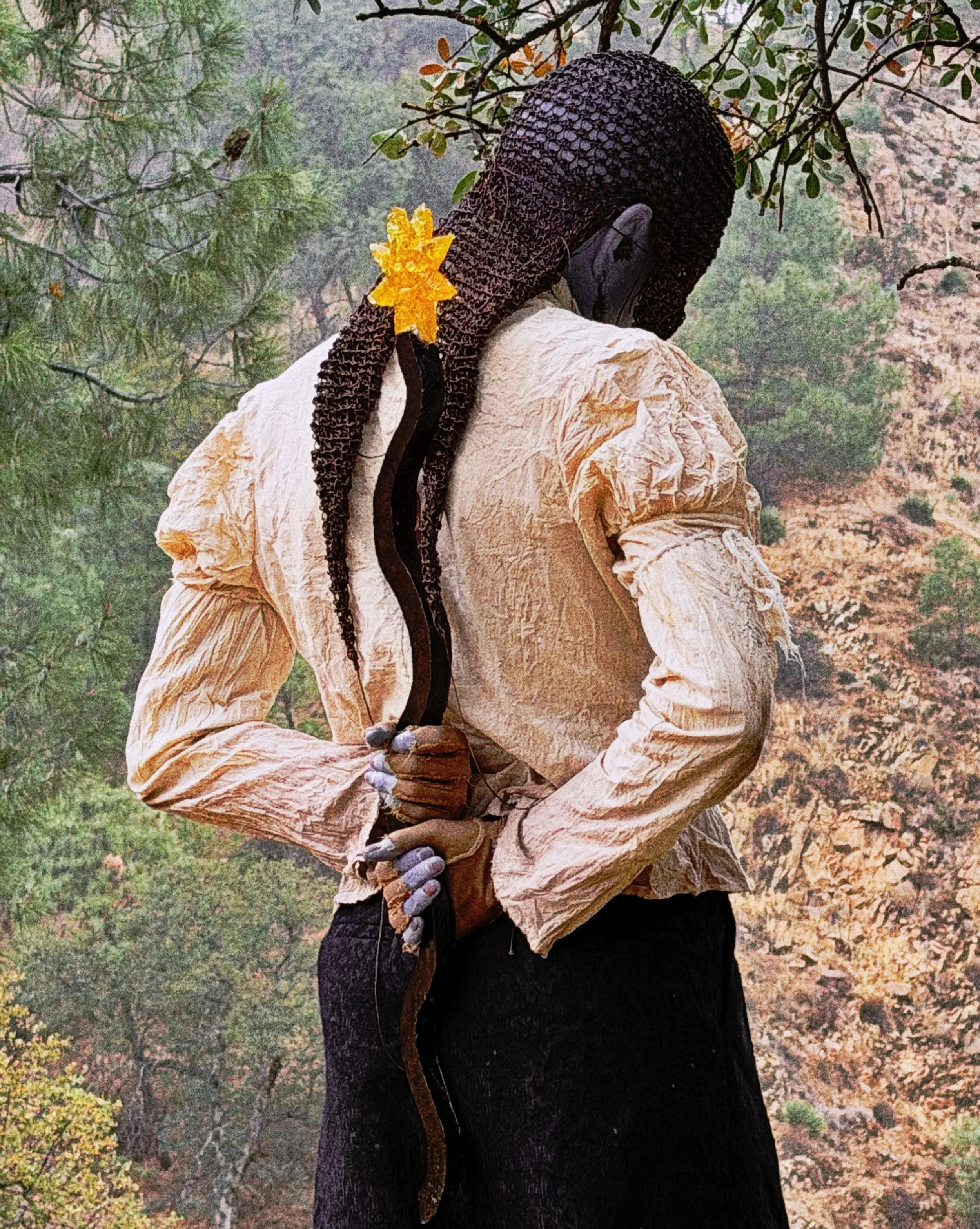 SIM wearing an Auntie Flew crocheted hat, holding a wavy purple magic resin wand with a yellow resin sun attached to the top.