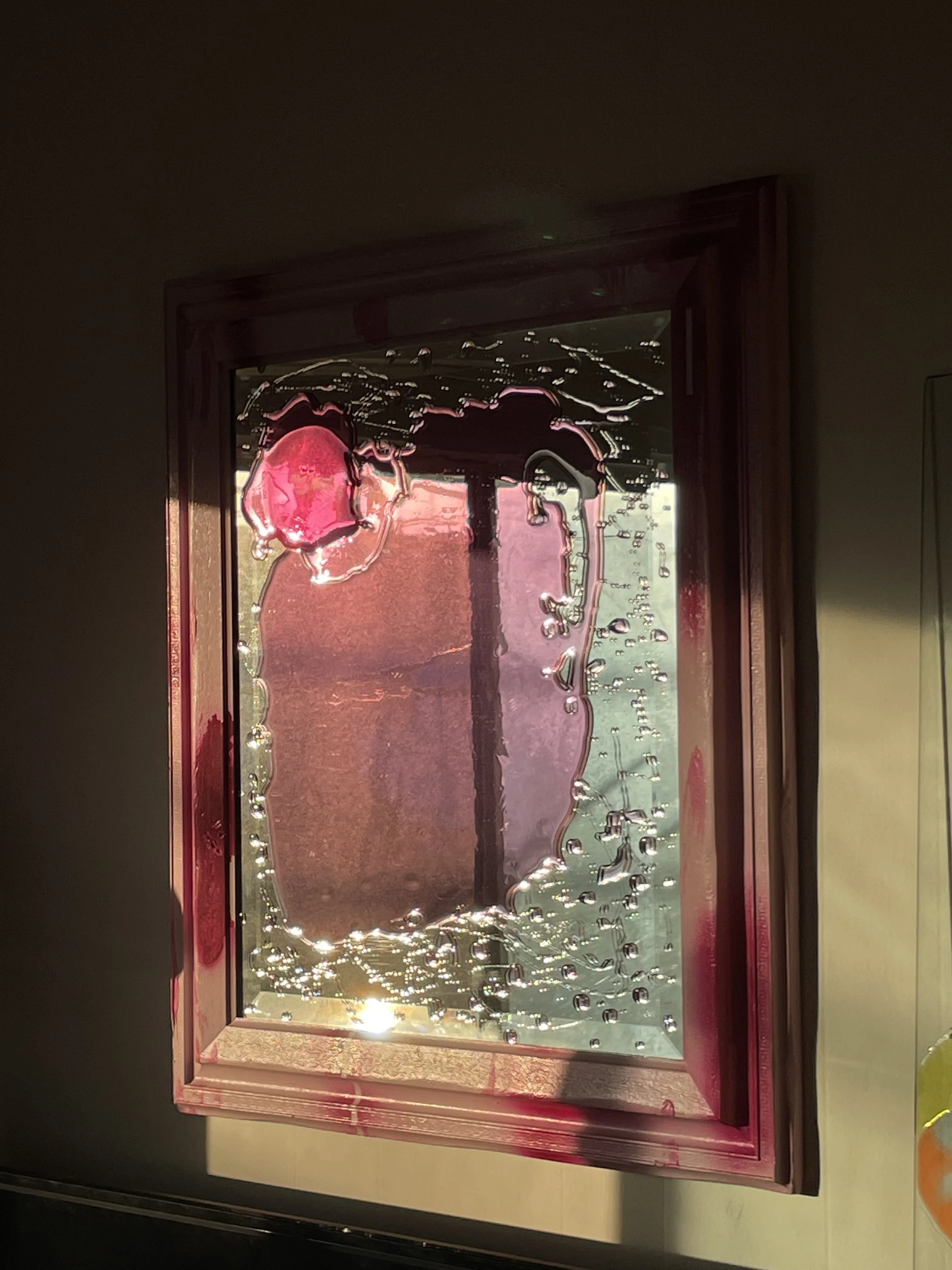 Pink resin mirror, framed in pink, with sunlight reflecting off.