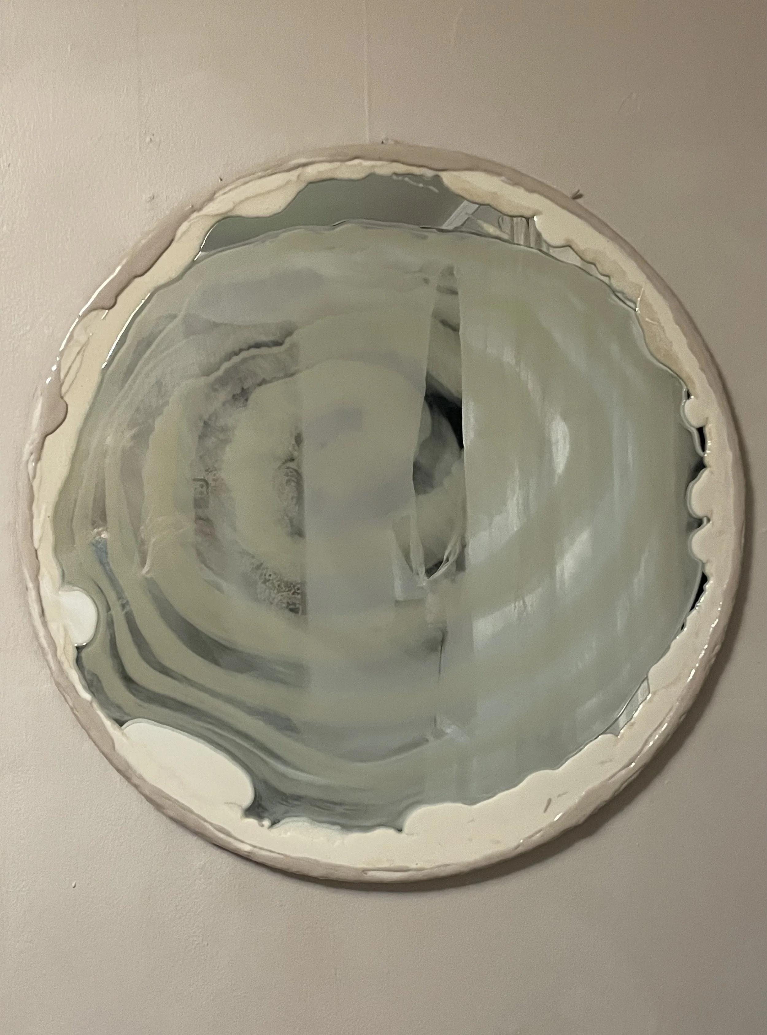 Close-up of a round, striped resin mirror resembling a cinnamon roll.