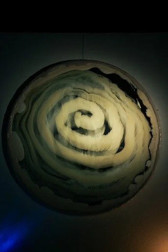 Close-up of a round, striped resin mirror resembling a cinnamon roll.