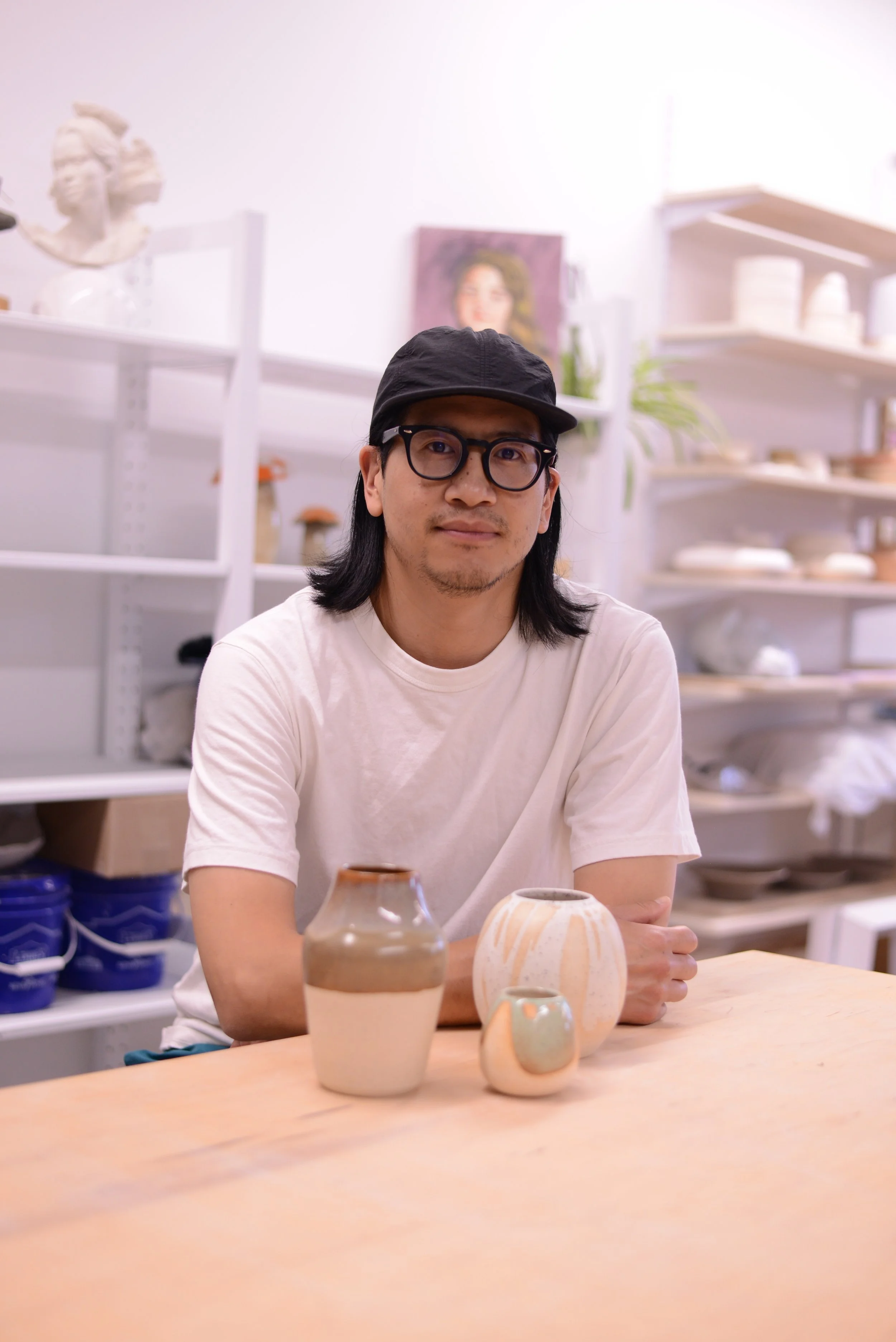 Pot Pot Studio co-owner Jon posing in front of his pottery pieces in the studio in Toronto, ON.