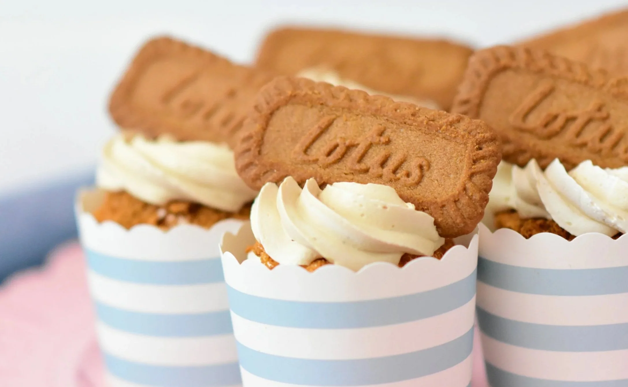Three cupcakes decorated with white frosting, topped with a rectangular Lotte cookie.