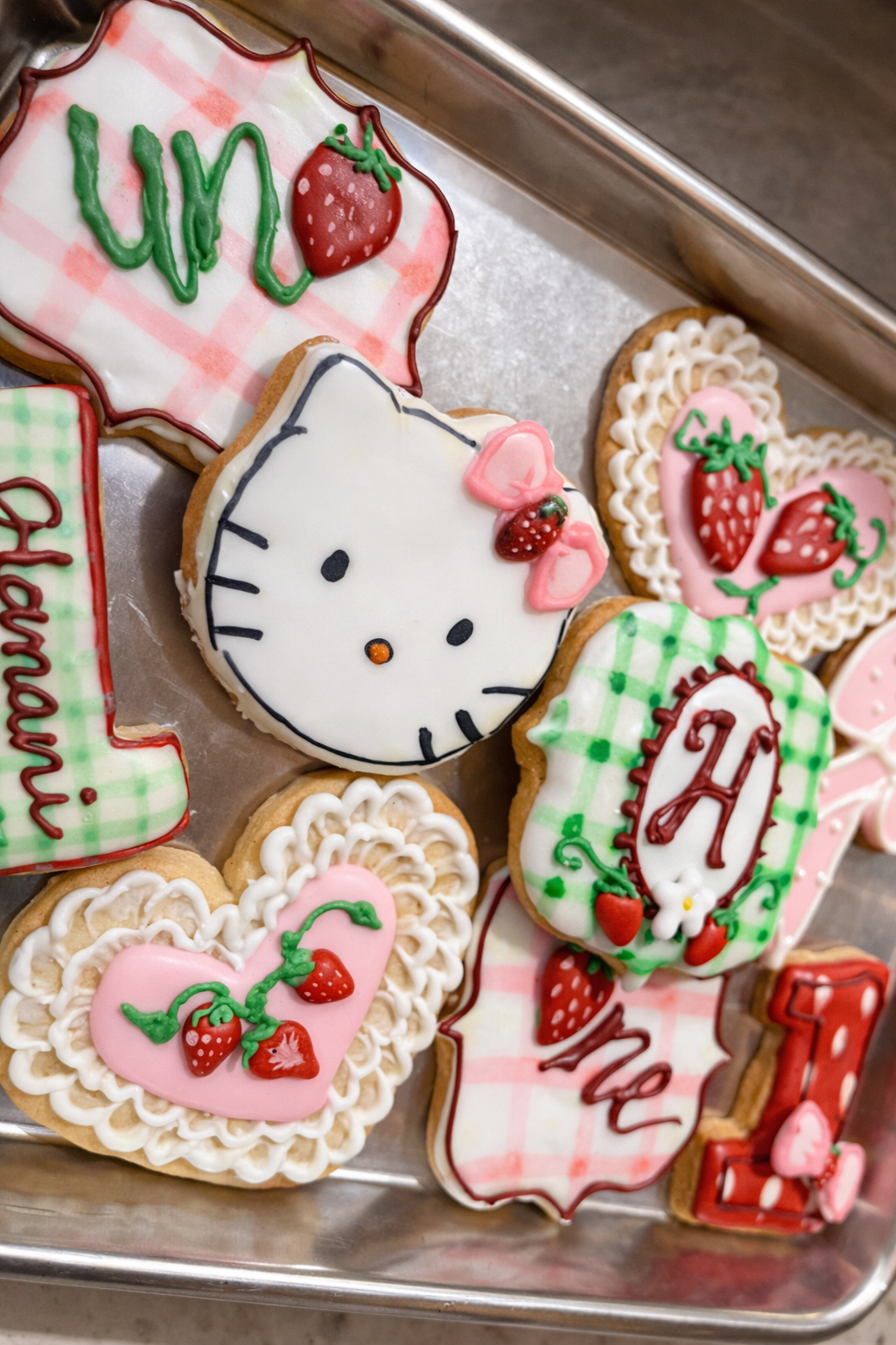 Decorated cookies featuring Valentine and strawberry themes, including a Hello Kitty cookie, strawberries, and romantic messages.