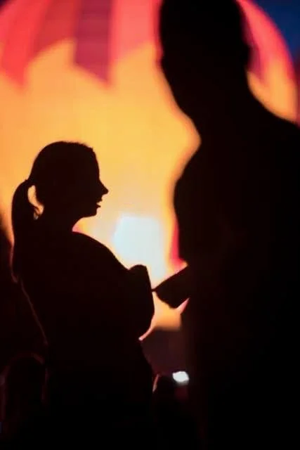 Silhouettes of a girl and a man against a colorful, blurry background.