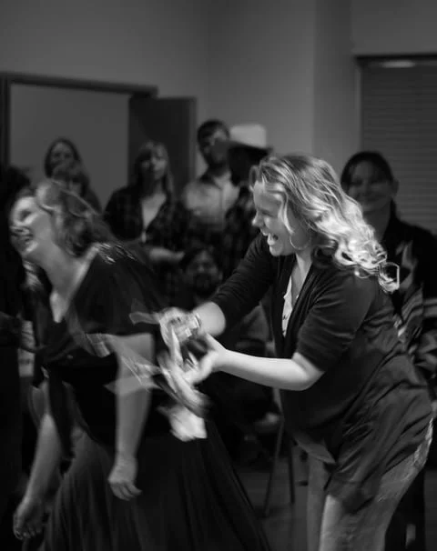 Group of women smiling and laughing while having fun at the throwing of the bouquet at a wedding.