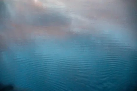 A calm body of water reflecting a cloudy sky.