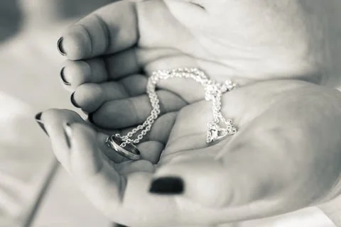 Close-up of a hand holding a pearl necklace with a heart-shaped pendant.