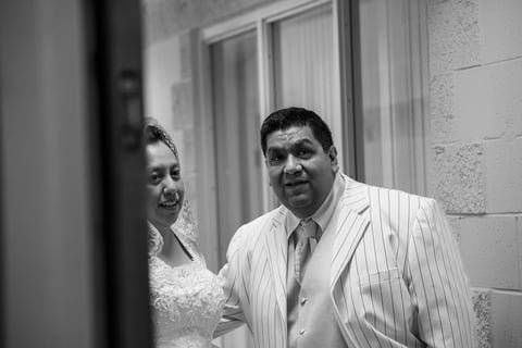 Black and white photo of a man and woman standing together indoors near a window, smiling.