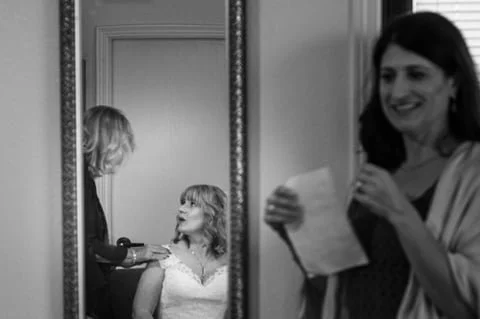 reflection of a bride looking shocked at family member with brides maid looks on.