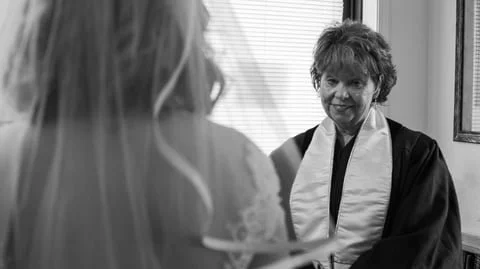 A bride listening to a woman, possibly a clergy member, during a wedding ceremony.