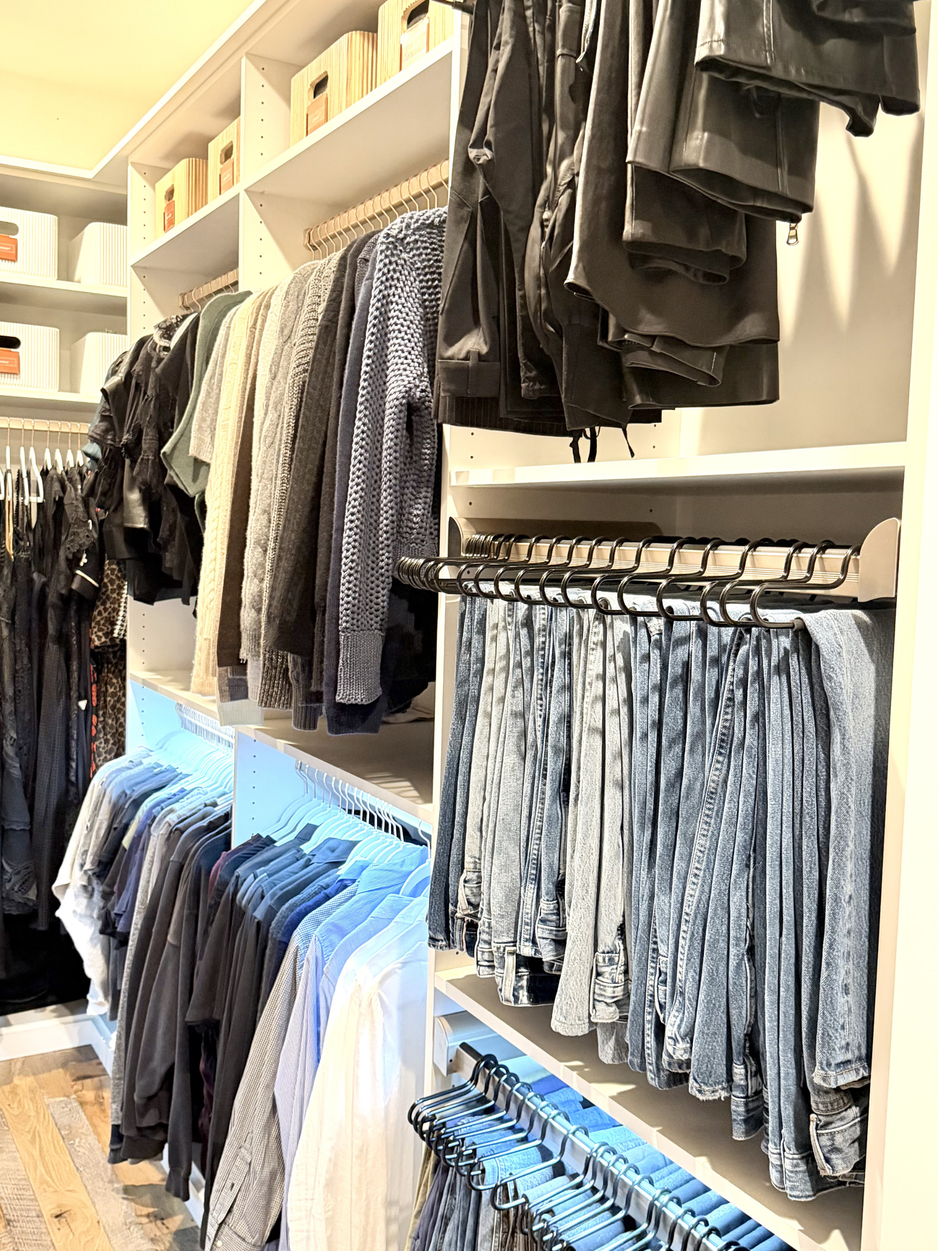 Color-coordinated walk-in closet with neatly arranged hanging clothes.