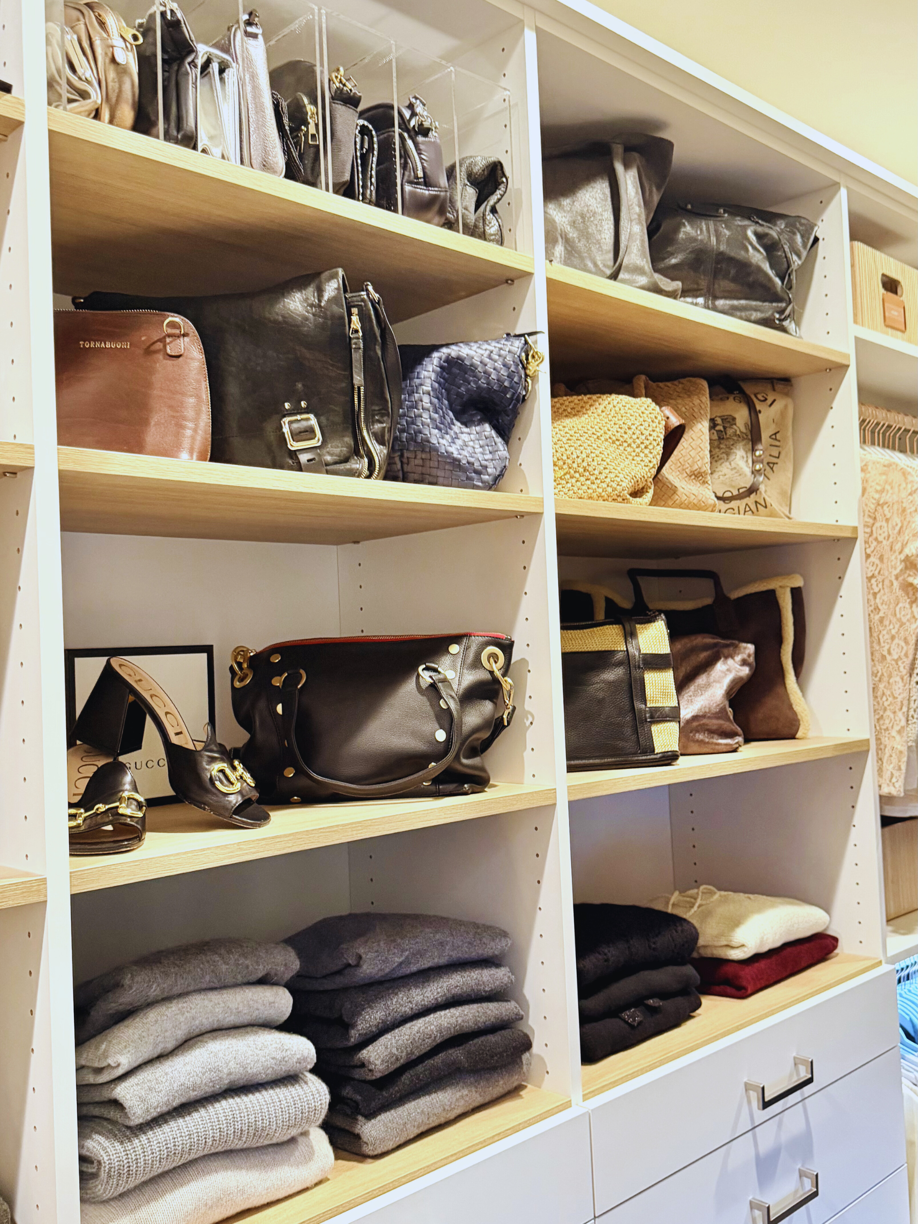 Organized closet shelves with handbags and neatly folded clothing
