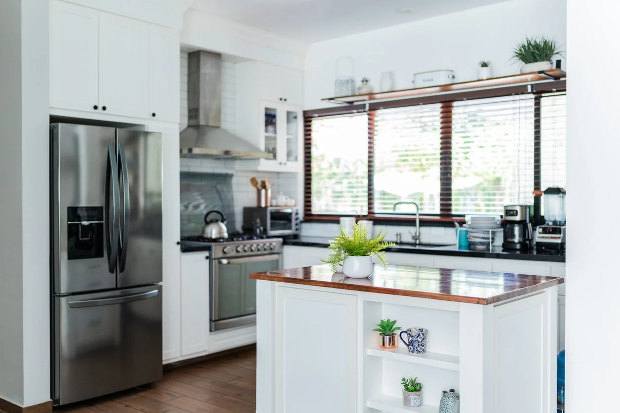 A clean organized kitchen with white cabinetry and stainless steel appliances.