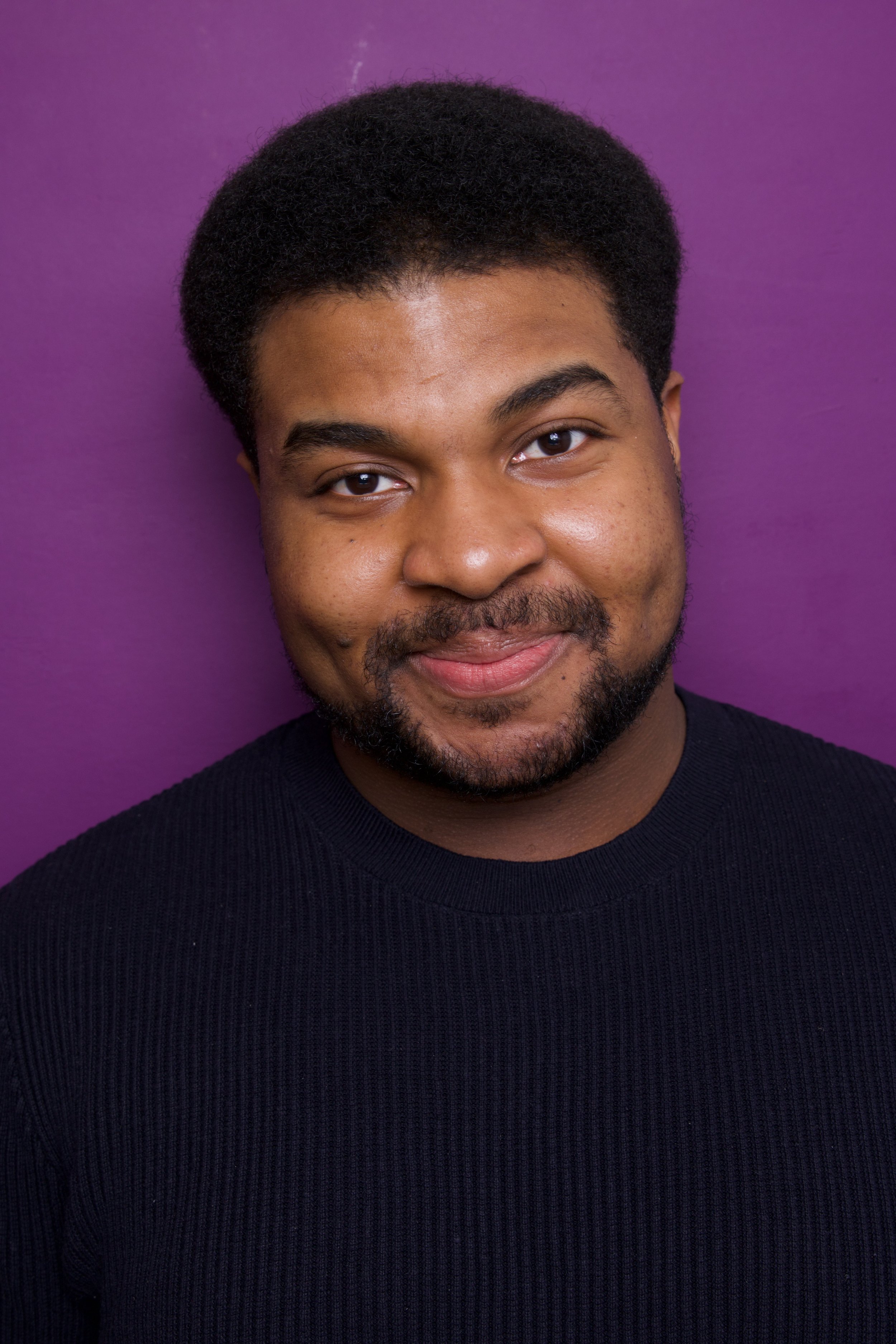A young man, Steven Rutledge, with a beard and short curly hair smiling against a purple background.

Taken by Robert Quiles (@robertredphoto on IG)