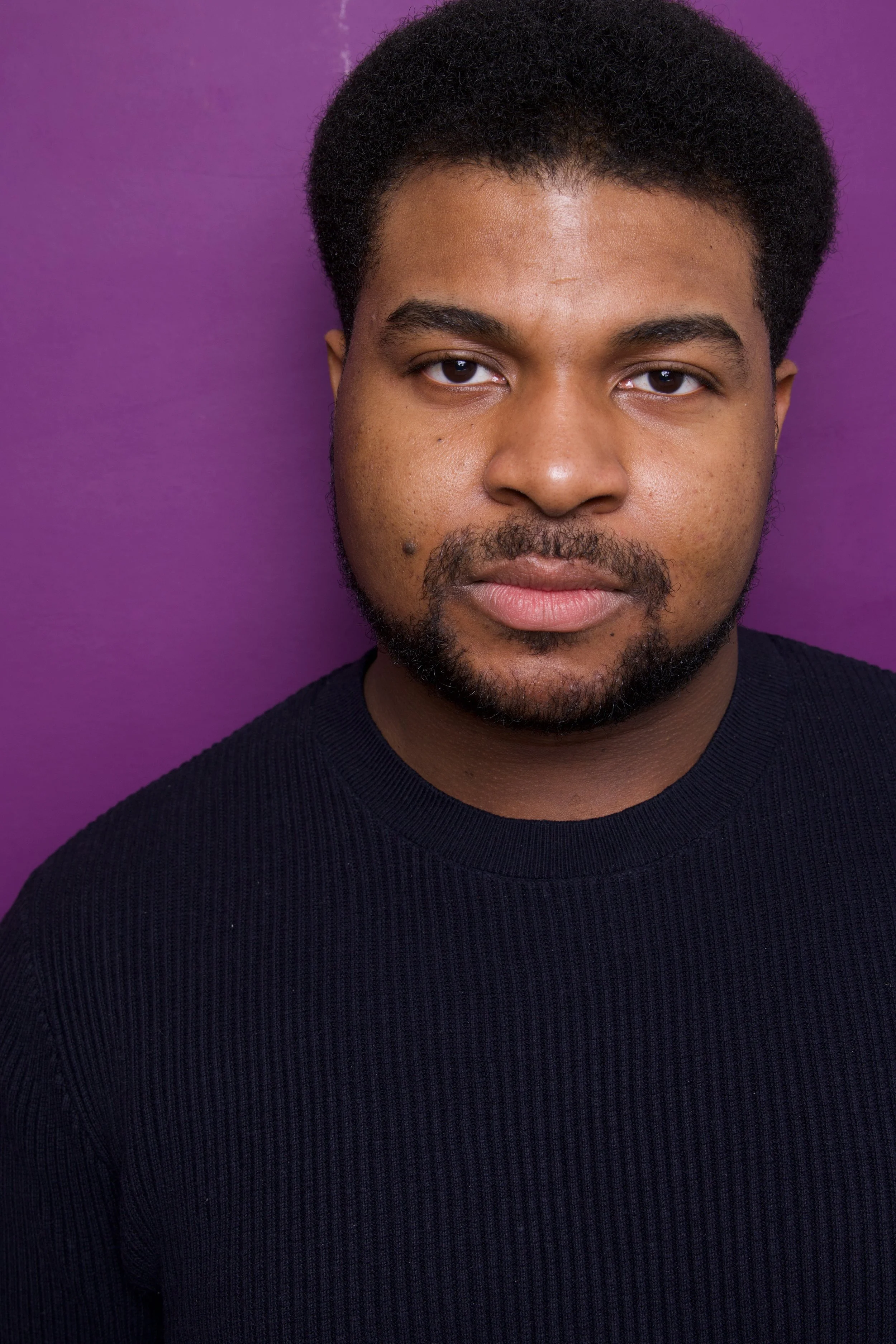 Close-up headshot of a young man, Steven Rutledge, with short curly black hair, a beard, and mustache, wearing a black tank top, standing against a purple background.

Taken by Robert Quiles (@robertredphoto on IG)