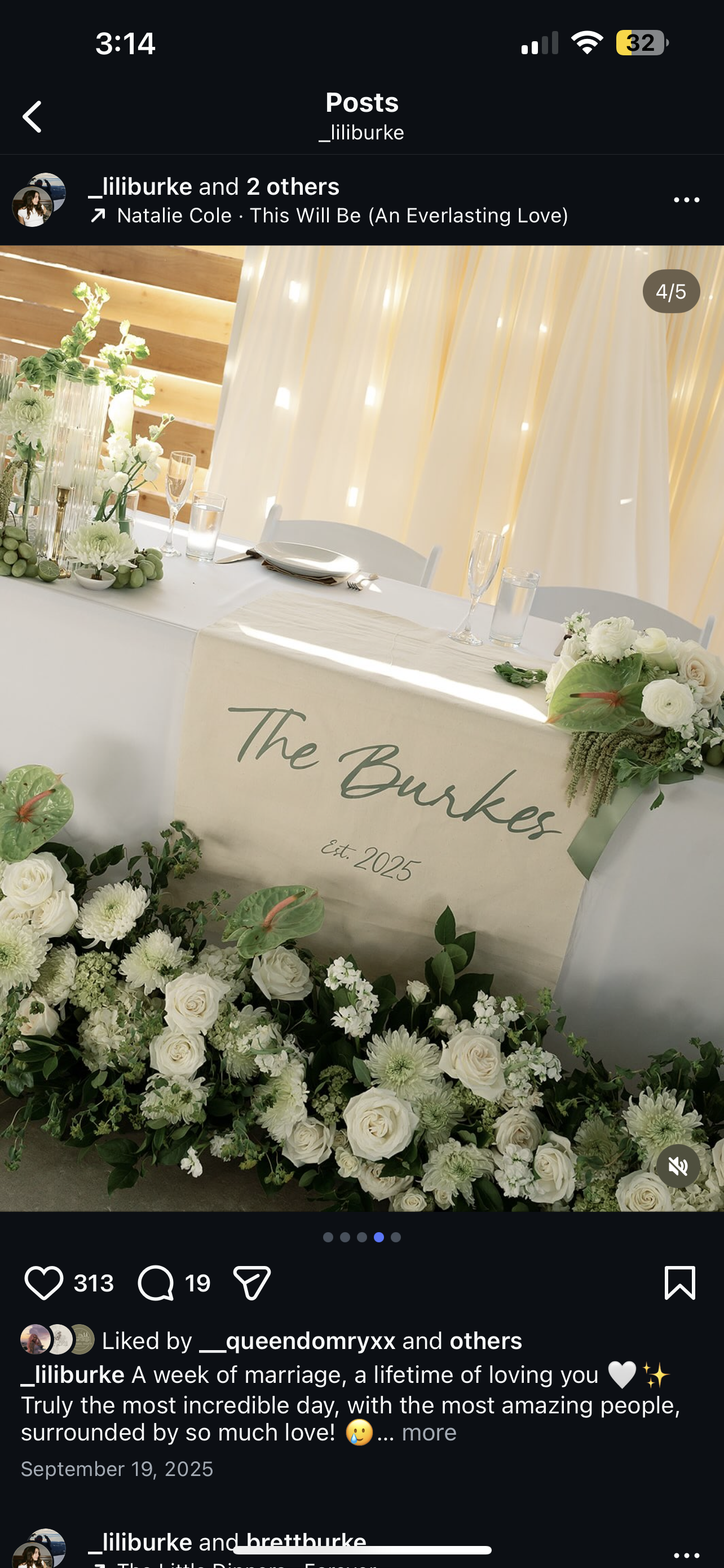 Wedding reception table decorated with white flowers, green foliage, and a personalized sign reading 'The Burkes Est. 2025'.