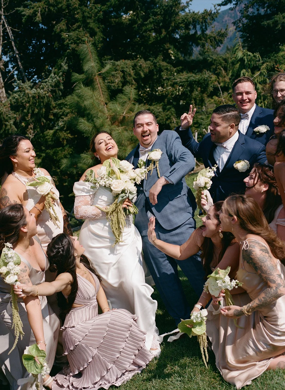 Decorated outdoor wedding reception table with white flowers, greenery, and a sign reading "The Burkes Est. 2025", set against a wooden privacy fence.