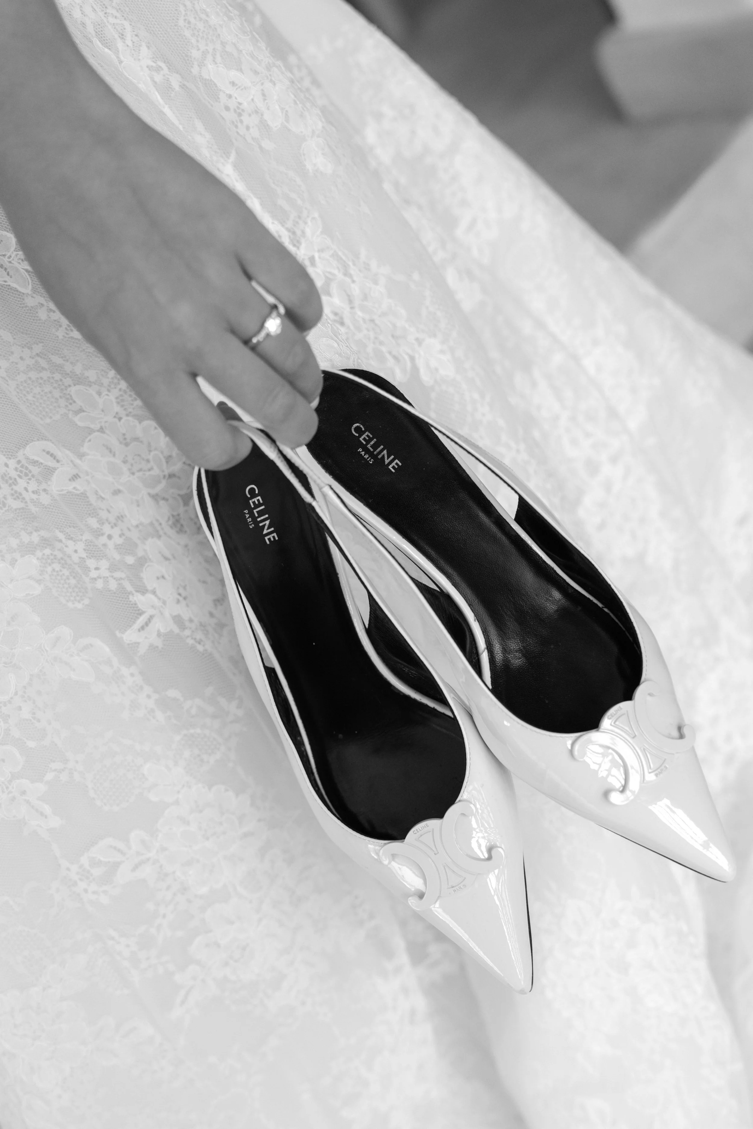 A hand holding a pair of black and white striped Celine Paris roller skates next to a lace tablecloth.