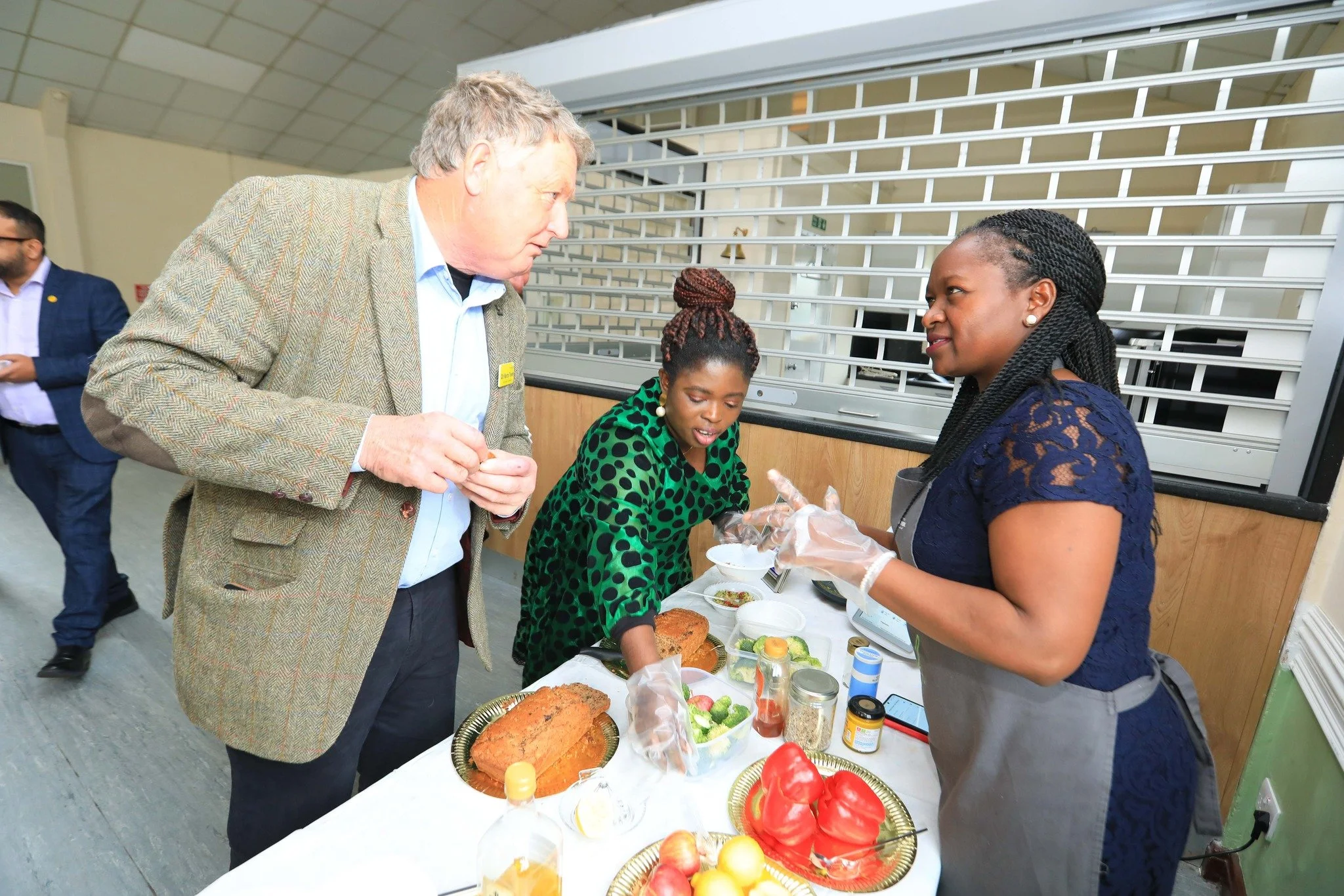 People at a food stall serving baked fish and vegetables at an indoor event.