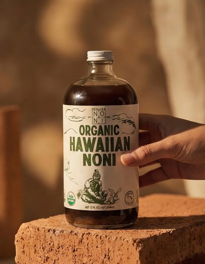 A hand holding a bottle of organic Hawaiian noni juice on a brick surface, with a blurred background.