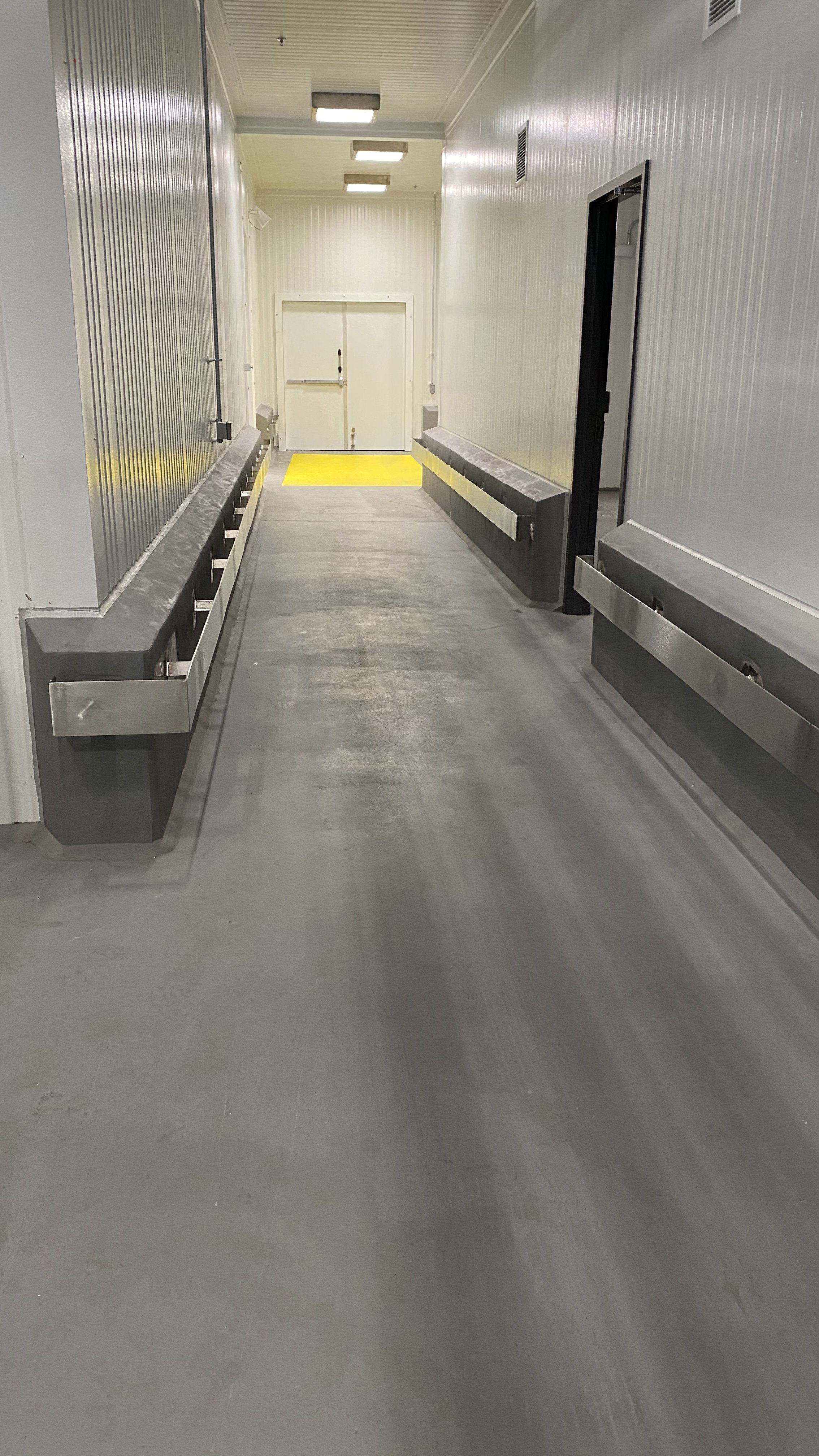 Empty cargo loading dock with metal railings and a yellow safety strip near the double doors.