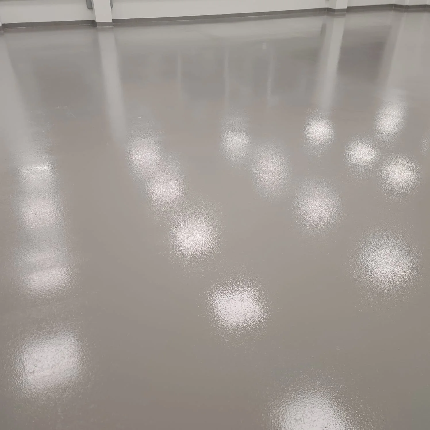 Polished concrete floor with reflected ceiling lights in an indoor space.