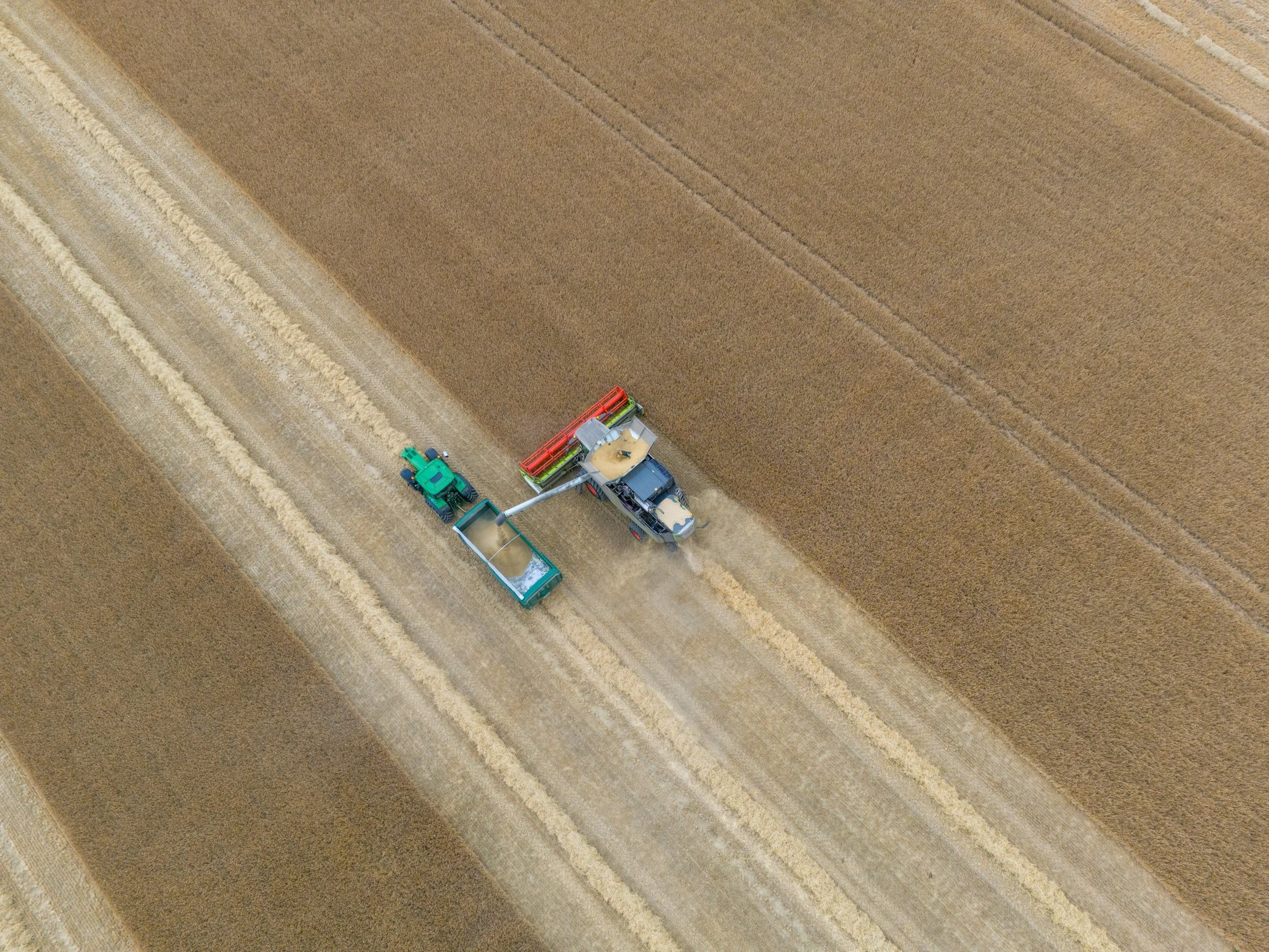 Aerial drone photo of combine unloading grain into a bank out wagon