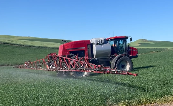 Self-propelled sprayer driving through a farm field