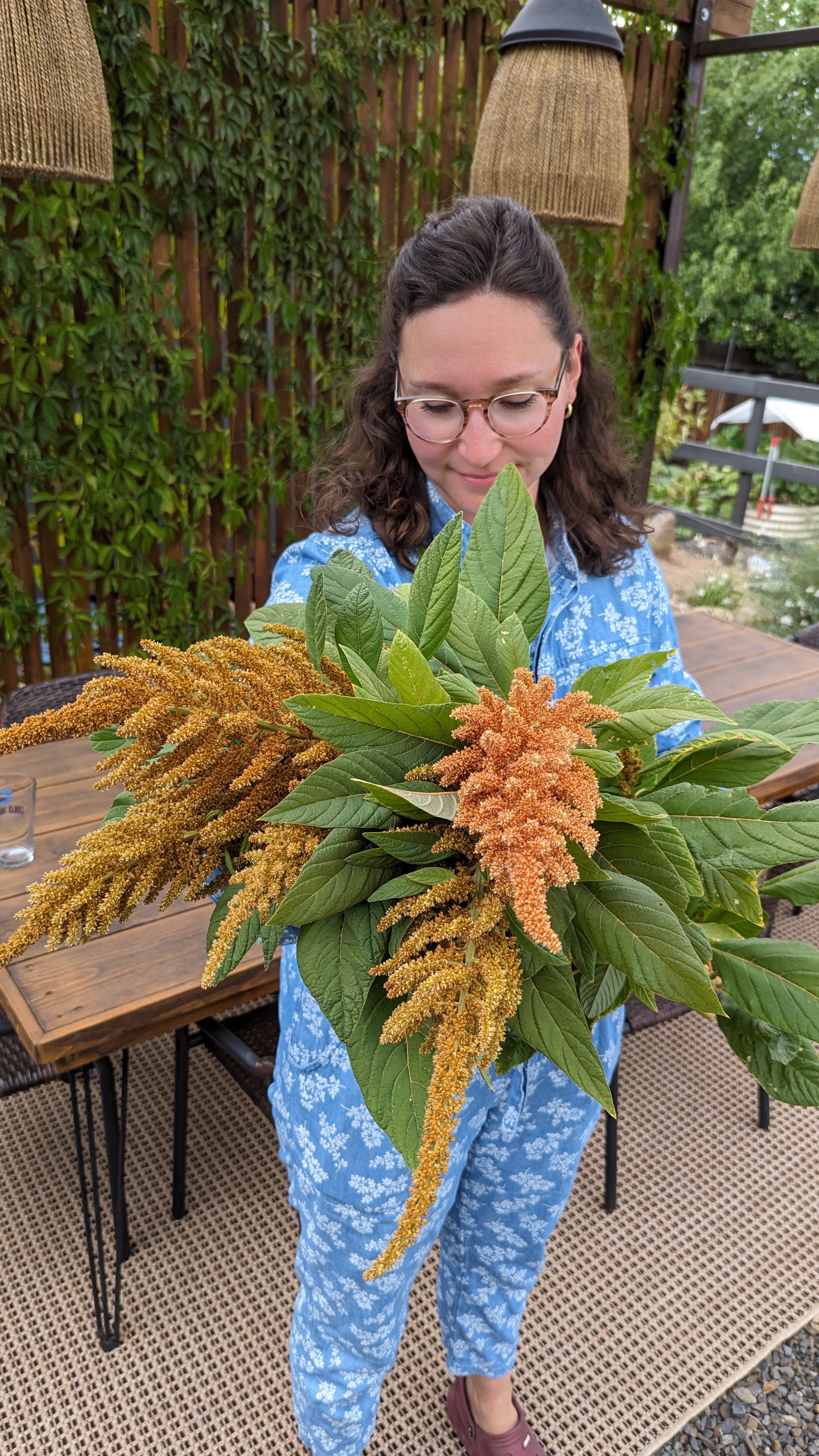 A large bouquet of green leaves and spiky peach-colored Amaranth outside.