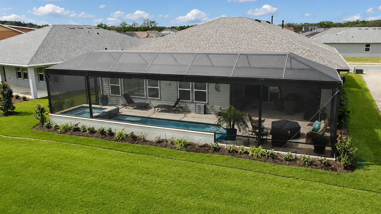 Backyard with a screen enclosure featuring a swimming pool, lounge chairs, potted plants, and outdoor furniture on a patio deck in front of a house.