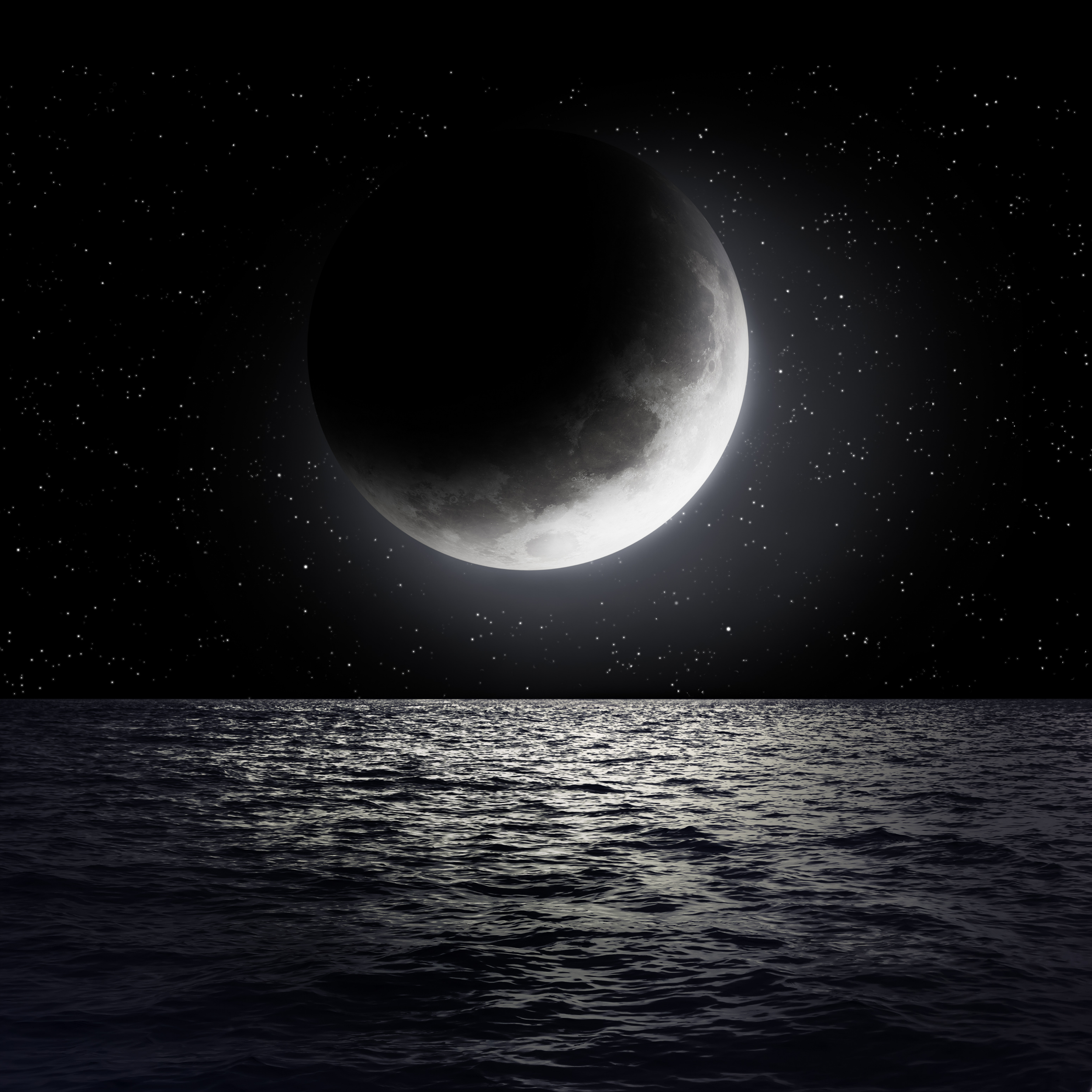 A view of the moon partially in shadow over calm ocean waters at night with a starry sky.