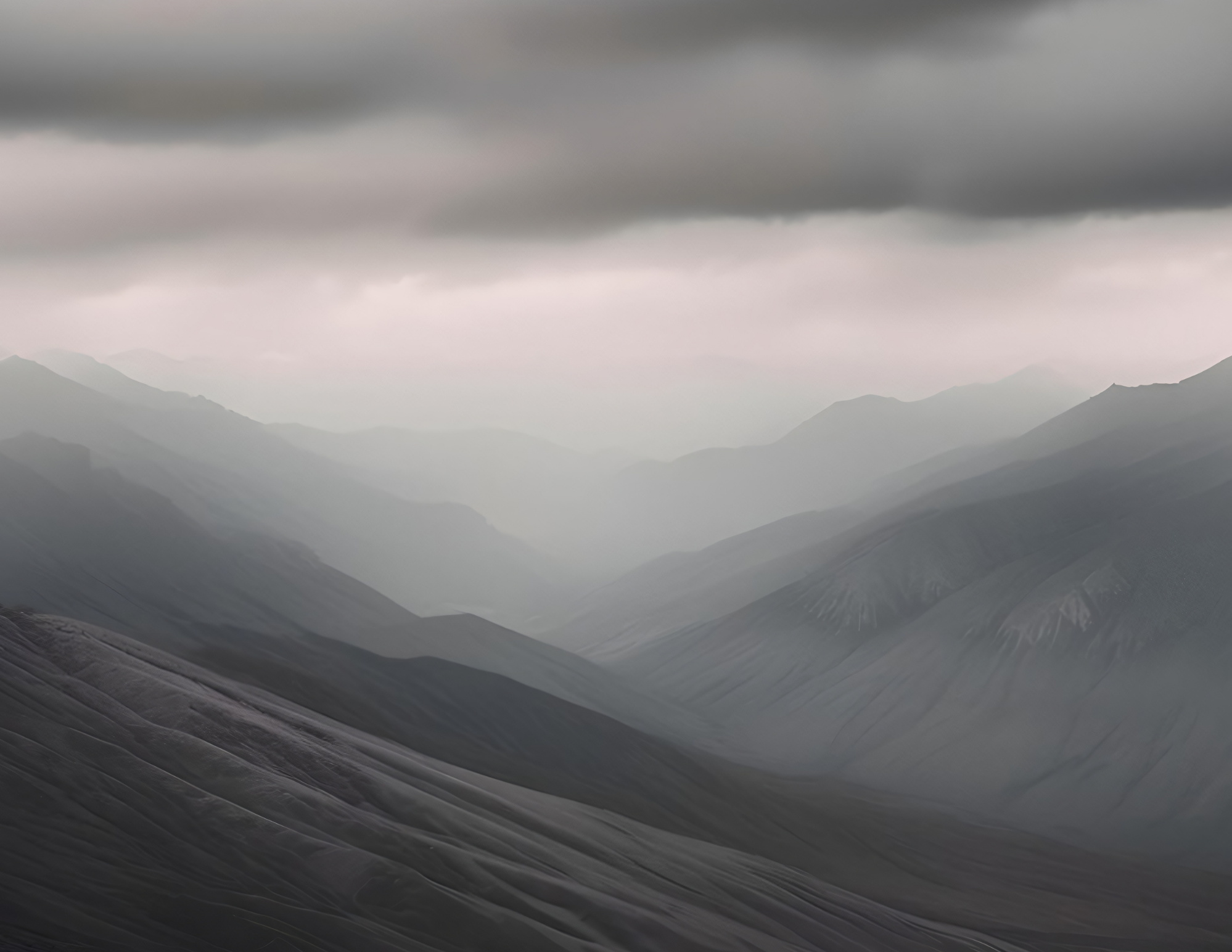 A misty mountain landscape with layered ridges and dark, overcast skies.
