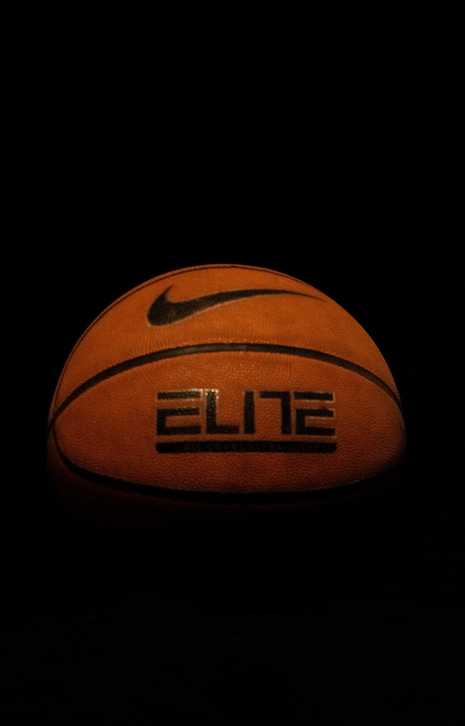 Dark background with a glow-in-the-dark Nike Elite basketball.