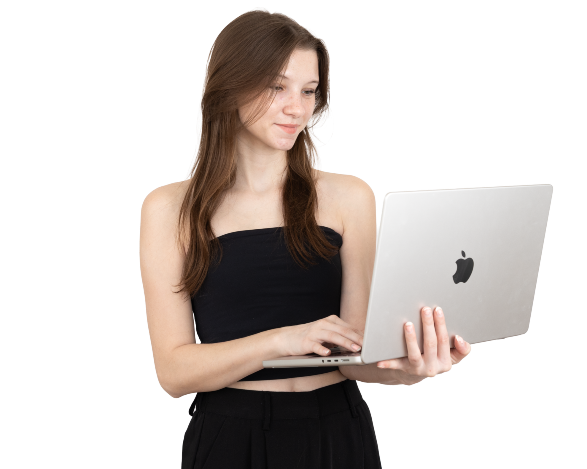 Young woman with long brown hair using a silver MacBook laptop, dressed in a black strapless top and matching black pants.